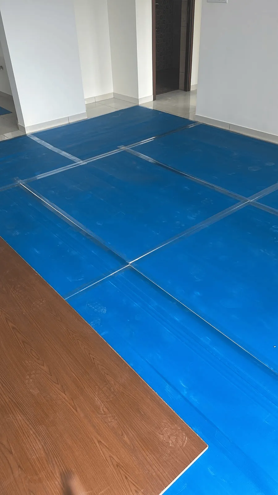 Blue floor protection sheet laid across a tiled floor before painting work